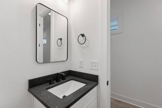 bathroom with baseboards, vanity, and wood finished floors