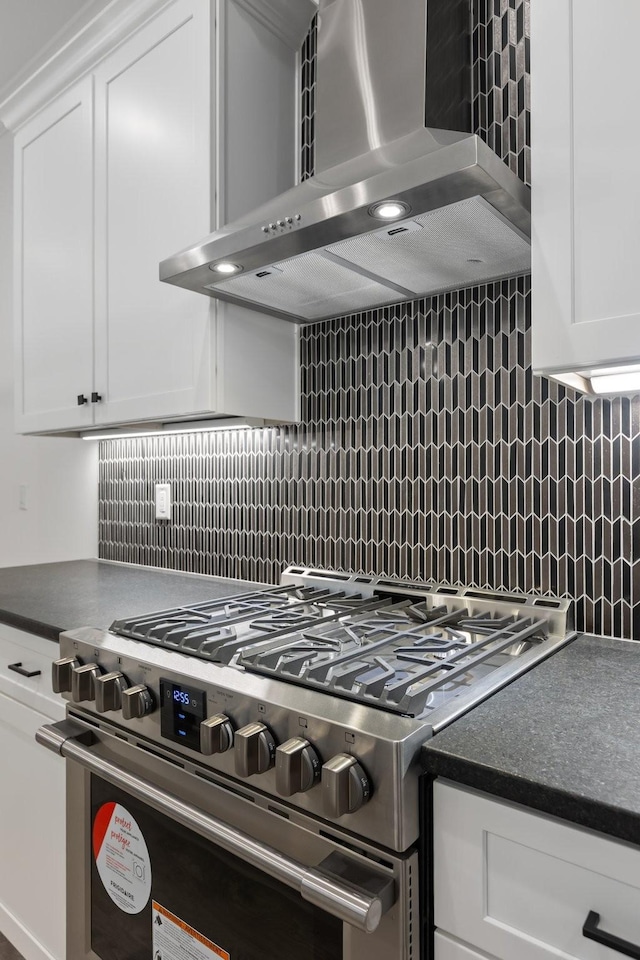 kitchen featuring wall chimney range hood, tasteful backsplash, high end range, and dark countertops