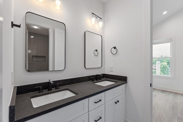 full bathroom featuring double vanity, wood finished floors, baseboards, and a sink