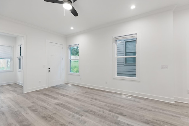 spare room with light wood-style flooring, crown molding, visible vents, baseboards, and ceiling fan