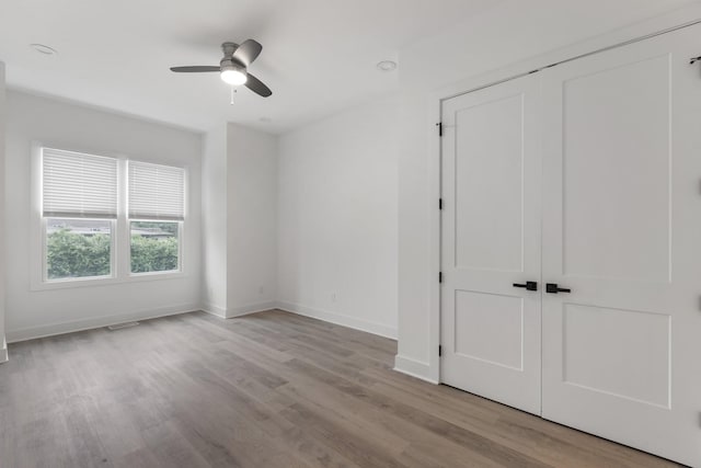 unfurnished bedroom with a ceiling fan, a closet, baseboards, visible vents, and wood finished floors