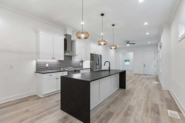 kitchen with a sink, stainless steel appliances, wall chimney range hood, backsplash, and dark countertops