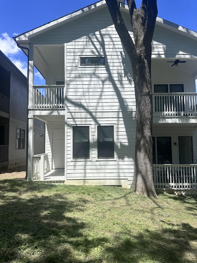 rear view of property with a balcony and a lawn