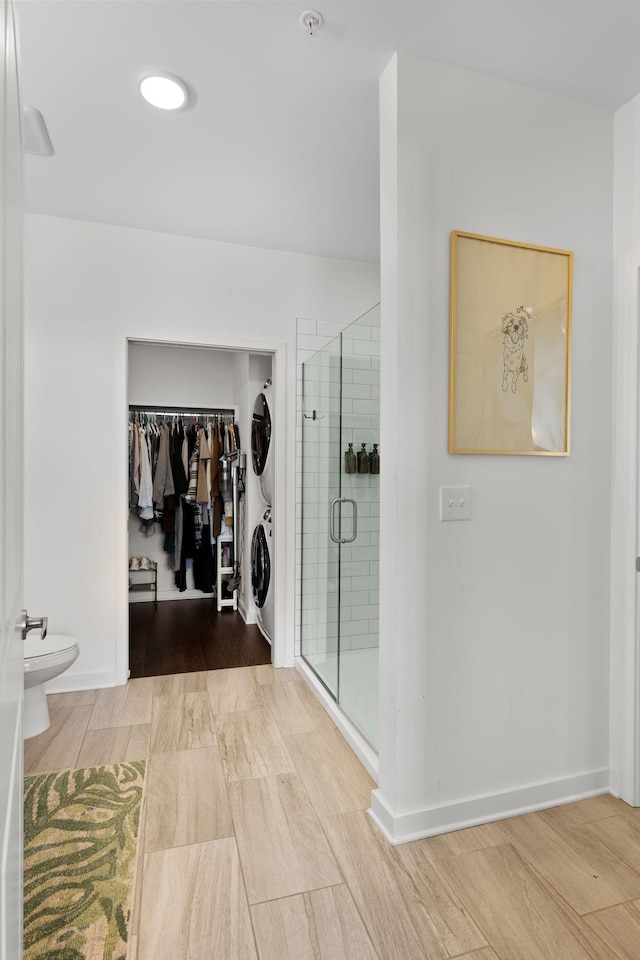 1677 54th Ave N Unit 318, Nashville, TN 37209 - bathroom featuring stacked washer and clothes dryer, a walk in closet, wood finished floors, a shower stall, and toilet