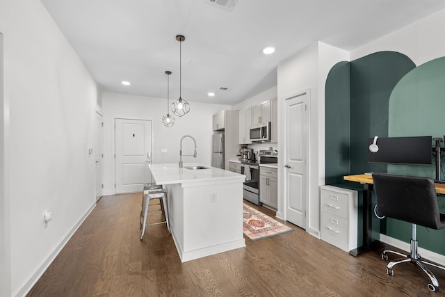 1677 54th Ave N Unit 318, Nashville, TN 37209 - kitchen with appliances with stainless steel finishes, a sink, a breakfast bar area, dark wood finished floors, and a center island with sink