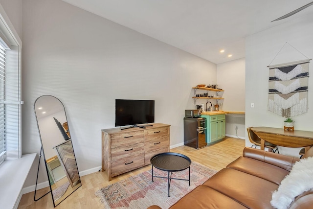 living room featuring light wood finished floors, baseboards, and recessed lighting
