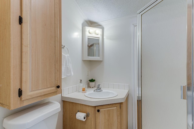 bathroom with vanity, ornamental molding, a textured ceiling, and toilet