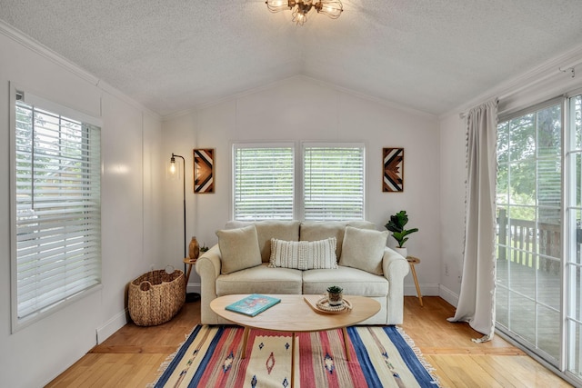 living area featuring light wood finished floors, crown molding, a textured ceiling, and plenty of natural light