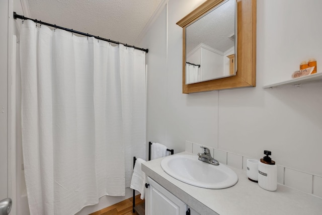 bathroom featuring a textured ceiling, shower / tub combo with curtain, and vanity
