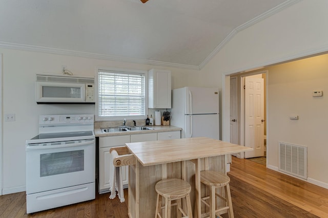 kitchen featuring white appliances, visible vents, a sink, a kitchen bar, and crown molding