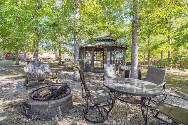 view of patio / terrace featuring an outdoor fire pit, outdoor dining area, fence, and a gazebo