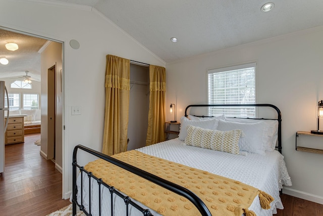 bedroom with vaulted ceiling, ornamental molding, and wood finished floors