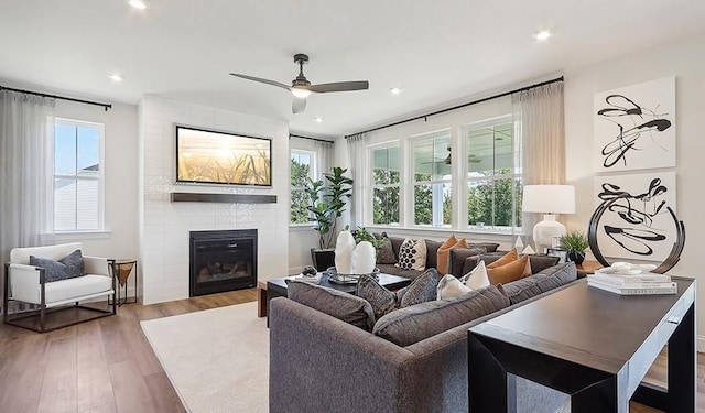 living room with a ceiling fan, recessed lighting, a large fireplace, and wood finished floors