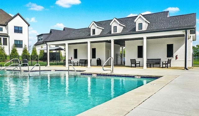 community pool with a patio area and fence