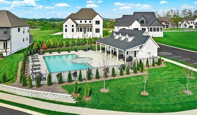 back of property with fence, a residential view, a community pool, a patio, and a lawn