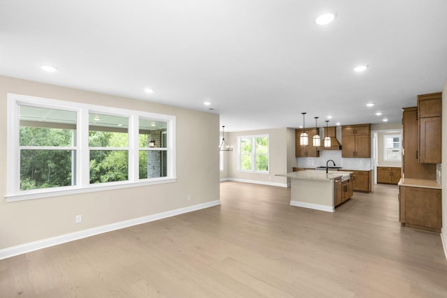 5958 Hunt Valley Dr, Spring Hill, TN 37174 - kitchen with a center island with sink, light wood-style flooring, open floor plan, brown cabinets, and pendant lighting