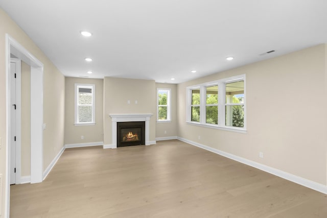 5958 Hunt Valley Dr, Spring Hill, TN 37174 - unfurnished living room with light wood-type flooring, plenty of natural light, recessed lighting, and a glass covered fireplace