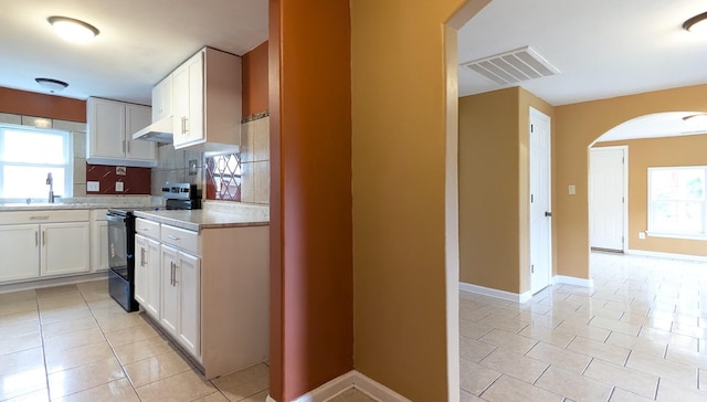 624 W Eastland St, Gallatin, TN 37066 - kitchen featuring black range with electric stovetop, arched walkways, light tile patterned flooring, light countertops, and under cabinet range hood