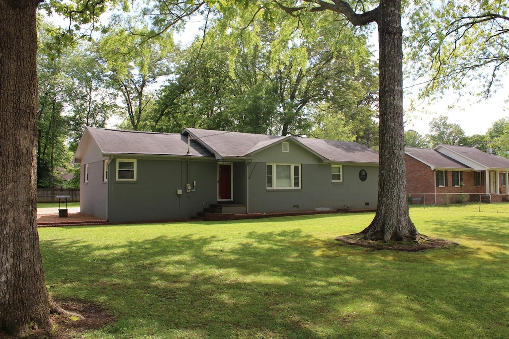 ranch-style house featuring crawl space, fence, a shingled roof, and a front yard