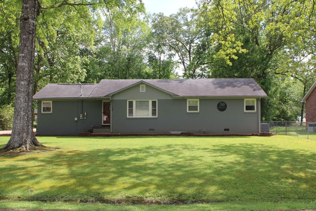 back of property featuring a lawn, roof with shingles, fence, and crawl space
