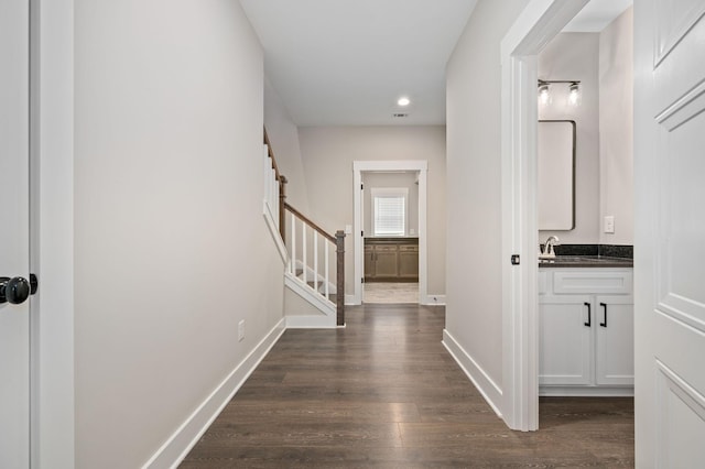 hallway with a sink, stairway, dark wood-style flooring, baseboards, and recessed lighting