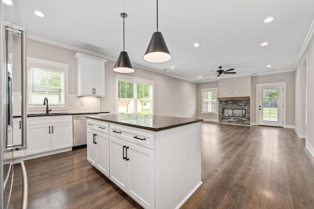 kitchen with a sink, dark wood-type flooring, a ceiling fan, stainless steel dishwasher, and dark countertops