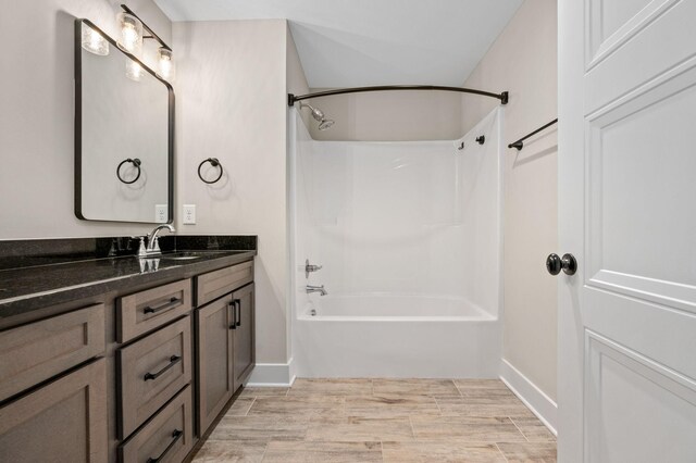bathroom featuring vanity, washtub / shower combination, baseboards, and wood finished floors