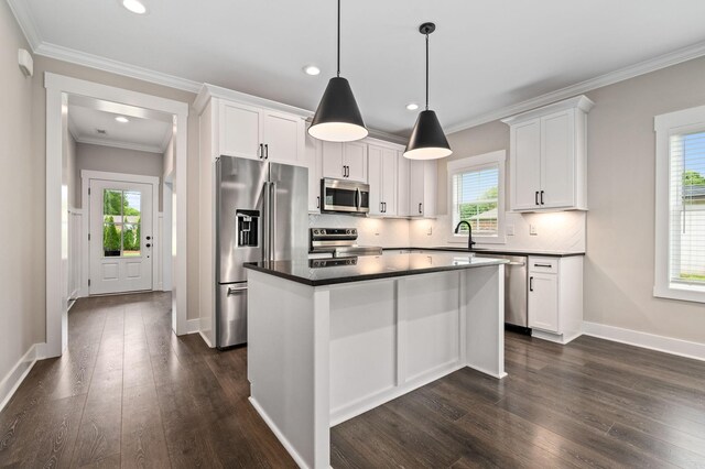kitchen with dark countertops, white cabinets, dark wood-style flooring, appliances with stainless steel finishes, and decorative backsplash