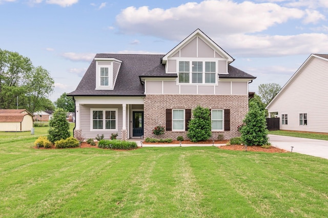 craftsman inspired home featuring roof with shingles, a front lawn, and brick siding
