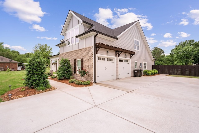 view of property exterior with an attached garage, fence, concrete driveway, board and batten siding, and brick siding
