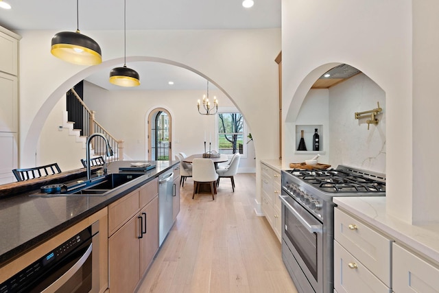 736 Douglas Ave, Nashville, TN 37207 - kitchen featuring light wood finished floors, dark stone countertops, appliances with stainless steel finishes, and a sink