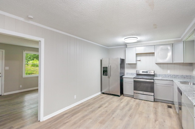kitchen with a sink, stainless steel appliances, a textured ceiling, light wood-type flooring, and crown molding