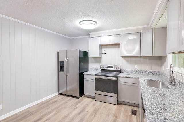 kitchen with light wood-type flooring, appliances with stainless steel finishes, ornamental molding, and a sink