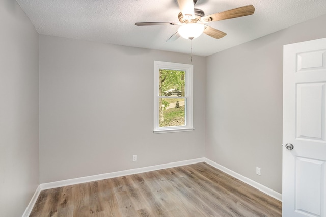 spare room featuring a textured ceiling, baseboards, light wood-style flooring, and a ceiling fan