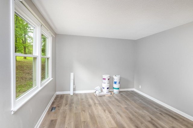 spare room featuring light wood finished floors, baseboards, and visible vents