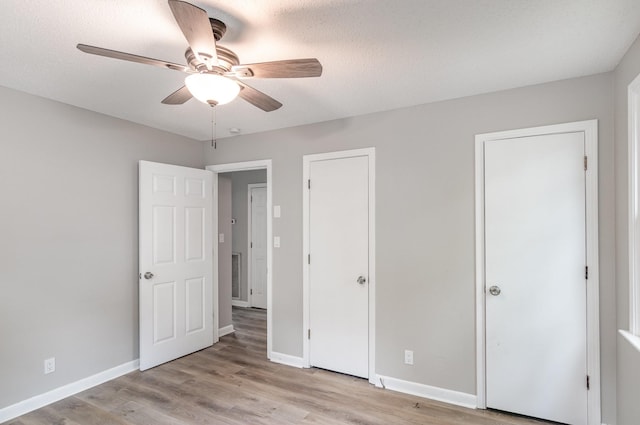 unfurnished bedroom featuring ceiling fan, baseboards, and wood finished floors