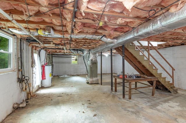 below grade area with water heater, heating unit, stairs, and concrete block wall