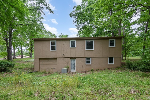 back of house with central air condition unit, a garage, and stucco siding