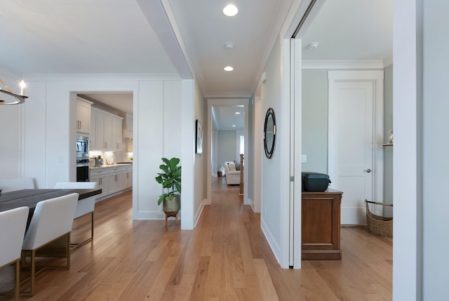 corridor with baseboards, recessed lighting, light wood finished floors, and crown molding