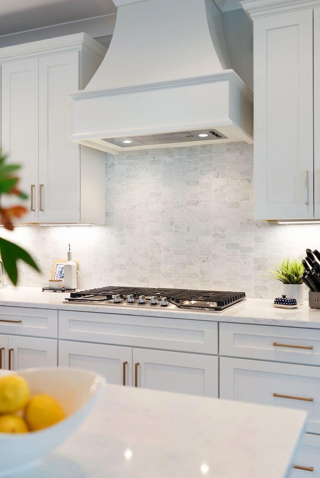kitchen with premium range hood, stainless steel gas stovetop, white cabinetry, and light countertops