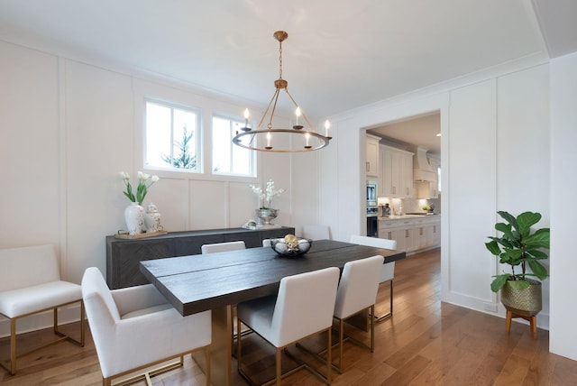 dining space with a notable chandelier, a decorative wall, and wood finished floors