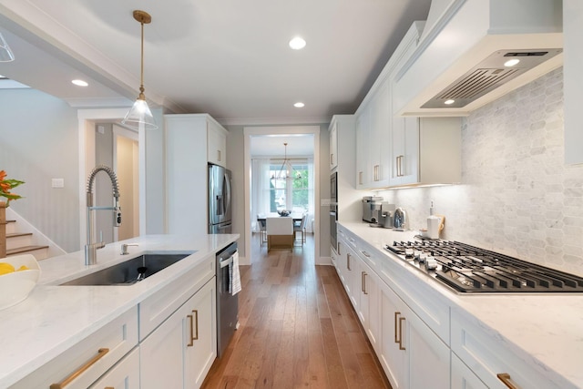 kitchen with a sink, stainless steel appliances, hanging light fixtures, and white cabinetry