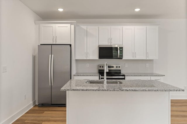 kitchen with a sink, light wood finished floors, stainless steel appliances, and white cabinetry