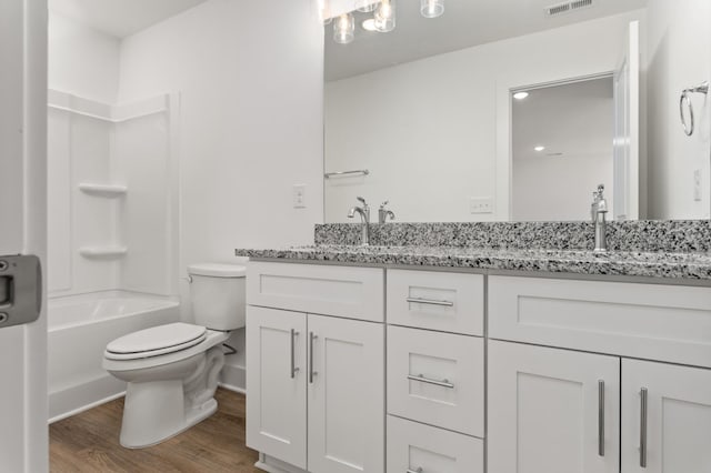 bathroom with toilet, visible vents, a sink, double vanity, and wood finished floors