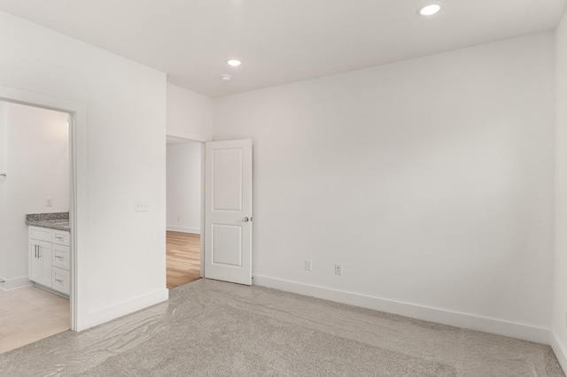 unfurnished bedroom with light colored carpet, baseboards, and recessed lighting