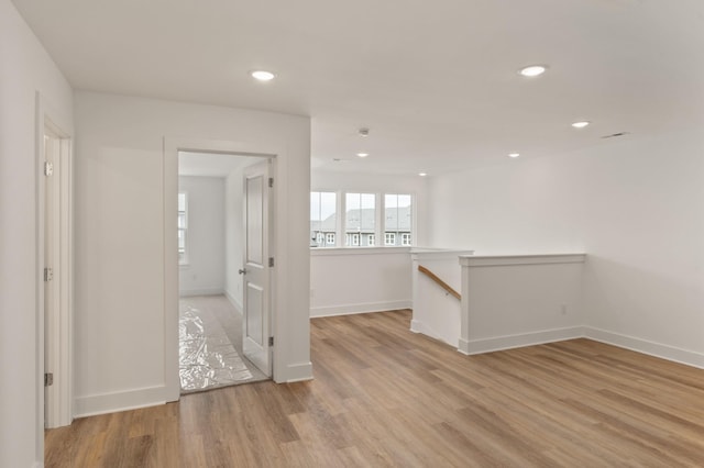empty room with light wood-style flooring, baseboards, and recessed lighting