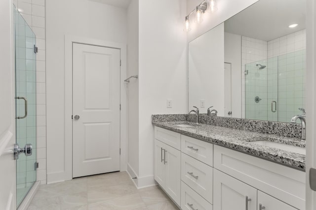 bathroom featuring double vanity, baseboards, a stall shower, and a sink