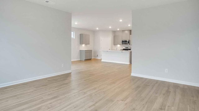 unfurnished living room featuring light wood finished floors, baseboards, and recessed lighting