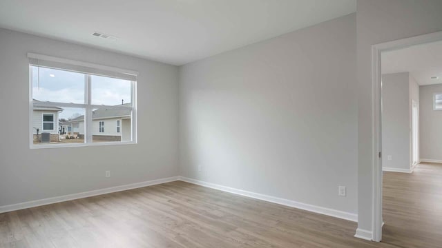 empty room with visible vents, wood finished floors, and baseboards