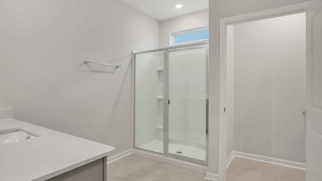 full bath featuring a stall shower, vanity, and baseboards